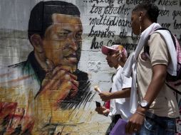 Jóvenes caminan por las calles de Caracas, donde abundan los murales en apoyo a Hugo Chávez. REUTERS  /