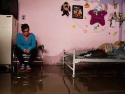 Una joven se sienta en el interior de su casa, afectada por las inundaciones. ARCHIVO  /