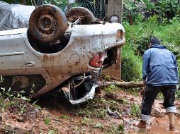 Un hombre observa un carro volcado por las lluvias. EFE  /