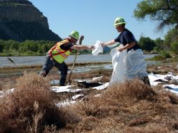 Contratistas de la compañía colocan almohadillas absorbentes para recoger el combustible vertido. AP  /