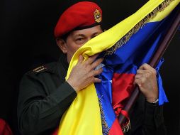 El gobernante de Venezuela besa la bandera de su país, en el “Balcón del pueblo”, luego del discurso que dio a sus seguidores. AFP  /