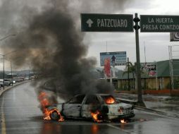 Uno de los vehículos incendiados usados para bloquear una vialidad. EFE  /
