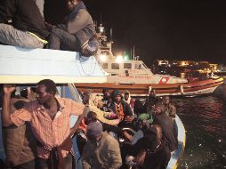 Inmigrantes permanecen sentados en uno de los cuatro barcos que llegaron a la isla de Lampedusa. EFE  /