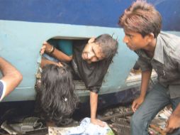 Los pasajeros salen por las ventanas; algunos hicieron sogas con pañuelos para abandonar el convoy. EFE  /