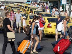 Viajeros pasan junto a taxis estacionados afuera del puerto de El Pireo, a las afueras de Atenas. EFE  /