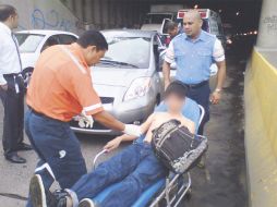 Édgar es atendido por paramédicos después de salvarse; atrás, el carro sobre el que cayó. ESPECIAL  /