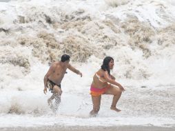 Un par de bañistas huyen de las olas altas que provocó el ciclón en Acapulco, Guerrero. NTX  /