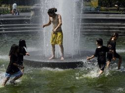 Personas se refrescan en una fuente en Nueva York. Ante la fuerte humedad, la sensación térmica supera los 46 grados en la ciudad. AFP  /