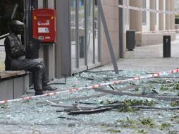 La imagen muestra restos de cristales y escombros frente a una estatua en Oslo, Noruega. EFE  /