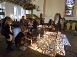 Un grupo de personas coloca veladoras en honor a las víctimas de la masacre, en la Catedral del Oslo. AP  /