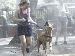 Teresa Smith y Clifford, un mastín labrador, corren bajo una regadera para refrescarse en Nueva York. AP  /