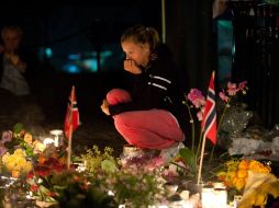 Una mujer permanece frente a las ofrendas dejadas a las afueras de la iglesia Domkirke. EFE  /