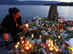 Una mujer enciende una vela en la costa frente a la isla donde 68 jóvenes murieron en uno de los atentados. REUTERS  /