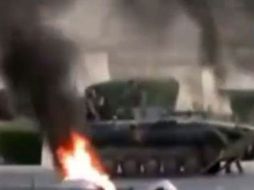 Foto tomada del canal de televisión Al Arabiya que muestra a un vehículo militar pasando junto a dos objetos en llamas. EFE  /
