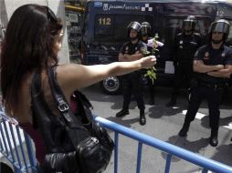 Una joven ''indignada'' ofrece flores a los agentes que impiden el acceso a la Puerta del Sol. EFE  /