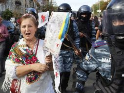 Una simpatizante de la ex primera ministra Yulia Timoshenko (i), camina junto a policías antidisturbios. EFE  /