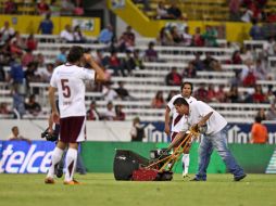 Los trabajadores del Estadio Jalisco limpian la 'marca' del equipo antes de iniciar el juego contra Estudiantes. ARCHIVO  /