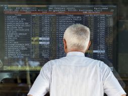 Un hombre observa en la pizarra eléctrica los movimientos de las acciones en Milán. AP  /