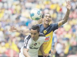 El jugador rojinegro Francisco Torres disputa la pelota con el americanista Édgar Castillo. AFP  /