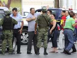 Habitantes regios, detrás de la línea de restricción, dialogan con militares que resguardan la zona de la masacre. REUTERS  /