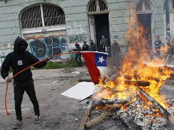 Un encapuchado quema una bandera chilena durante los disturbios posteriores a la marcha en Santiago. REUTERS  /