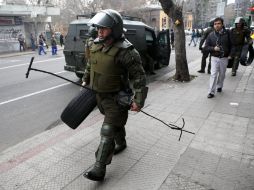 Un carabinero despeja las barricadas tras los disturbios posteriores a la marcha ayer, jueves 25, en Santiago de Chile. EFE  /