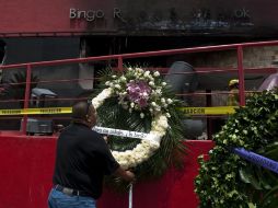 Un hombre coloca una corona de flores afuera de un casino en Monterrey, donde murieron al menos 53 personas tras un ataque. AFP  /