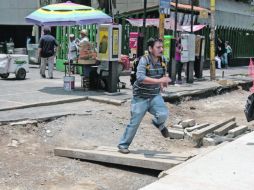 Ante las obras de repavimentación, los peatones deben cruzar las zanjas a través de tablones improvisados. A. HINOJOSA  /