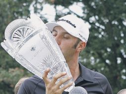 Dustin Johnson besa el trofeo ganado. AP  /