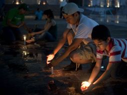 Personas encienden velas enfrente del Palacio de Gobierno, para exigir paz en el estado y en todo México. AP  /