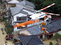 Miembros de la tripulación de un helicóptero de rescate ayudan a una persona aislada por un tifón. AP  /