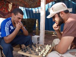 Rebeldes libios juegan ajedrez en la destruida base de la brigada liderada por Khamis Gadhafi, cerca a Bani Walid. EFE  /