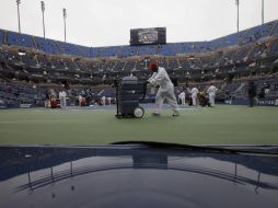 Intendentes tratan de retirar el agua que se ha acumulado en la cancha de tenis. AP  /