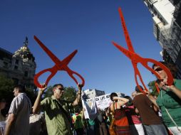 Profesores simbolizan los recortes de presupuesto en la educación pública con tijeras gigantes . REUTERS  /