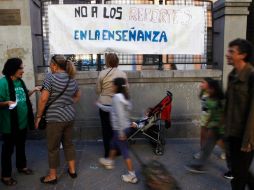 Ciudadanos de Madrid pasan frente a una manta de apoyo a la manifestación, colgada afuera de una escuela pública. REUTERS  /