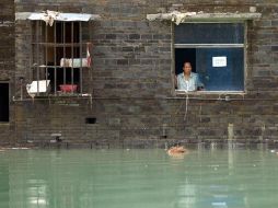 Un vecino mira al exterior de su casa y la calle inundada por las inundaciones en la provincia de Sichuan. EFE  /