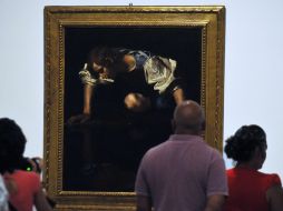 Varias personas observan el cuadro Narciso de Caravaggio. EFE  /