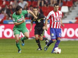 El centrocampista del Sporting Miguel de las Cuevas (d) controla el balón en presencia del defensa del Racing Christian Férnandez. EFE  /