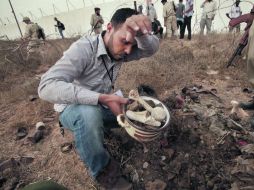 Un hombre recolecta restos humanos que fueron encontrados en una fosa común, presuntamente tras la masacre de 1996, en Trípoli. REUTERS  /