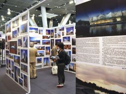 Varias personas observan el mural de fotografías y diseños instalados en el  Congres de Arquitectura. EFE  /