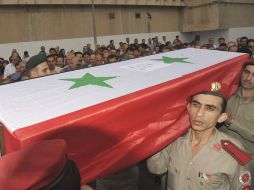 Oficiales cargan un ataúd en el funeral de al menos 13 soldados en Damasco, Siria. EFE  /