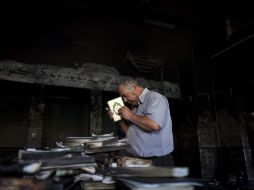 Un árabe ora con un Corán quemado en la mezquita incendiada. EFE  /