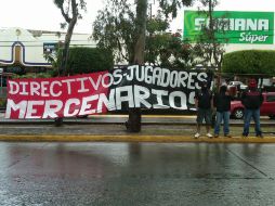 Los aficionaos atlistas, que se dieron cita en el Club Chapalita, permanecieron parados a un lado de su manta a pesar de la lluvia. NTX  /