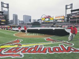 Trabajadores en el Busch Stadium de San Luis, despliegan una carpa para proteger el infield de la lluvia. AP  /
