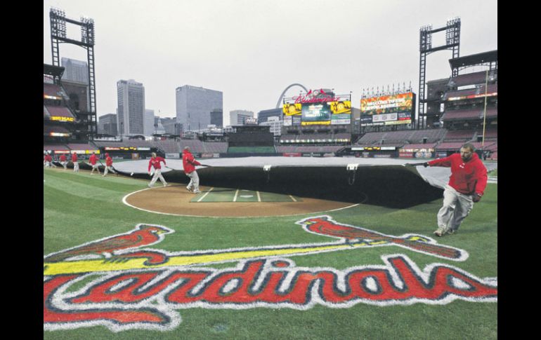 Trabajadores en el Busch Stadium de San Luis, despliegan una carpa para proteger el infield de la lluvia. AP  /