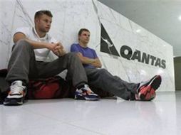 Pasajeros se quedan sentados en el mostrador de Qantas Airways para recepción de pasajeros y equipaje. AP  /