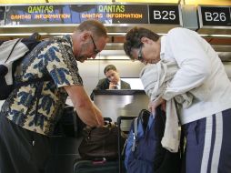 Pasajeros de Quantas acuden a un mostrador de la aerolínea para programar su vuelo. AP  /