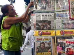 Una vendedora de un puesto de periódicos acomoda los diarios que tienen en la portada la muerte de Cano tras un enfrentamiento. AFP  /