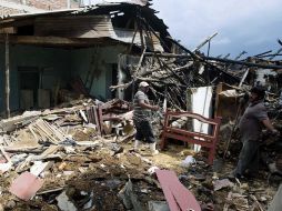 Hombres observan los destrozos en su casa luego de un ataque con explosivos en Piendamó, por presuntos guerrilleros de las FARC. EFE  /