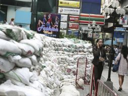 Una mujer habla por teléfono junto a un dique de contención formado por sacos de arena alrededor de un centro comercial en Bangkok.EFE  /